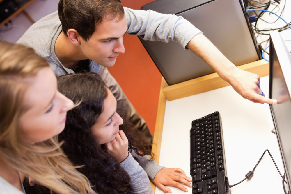 Estudantes que utilizam um computador em uma sala de informática