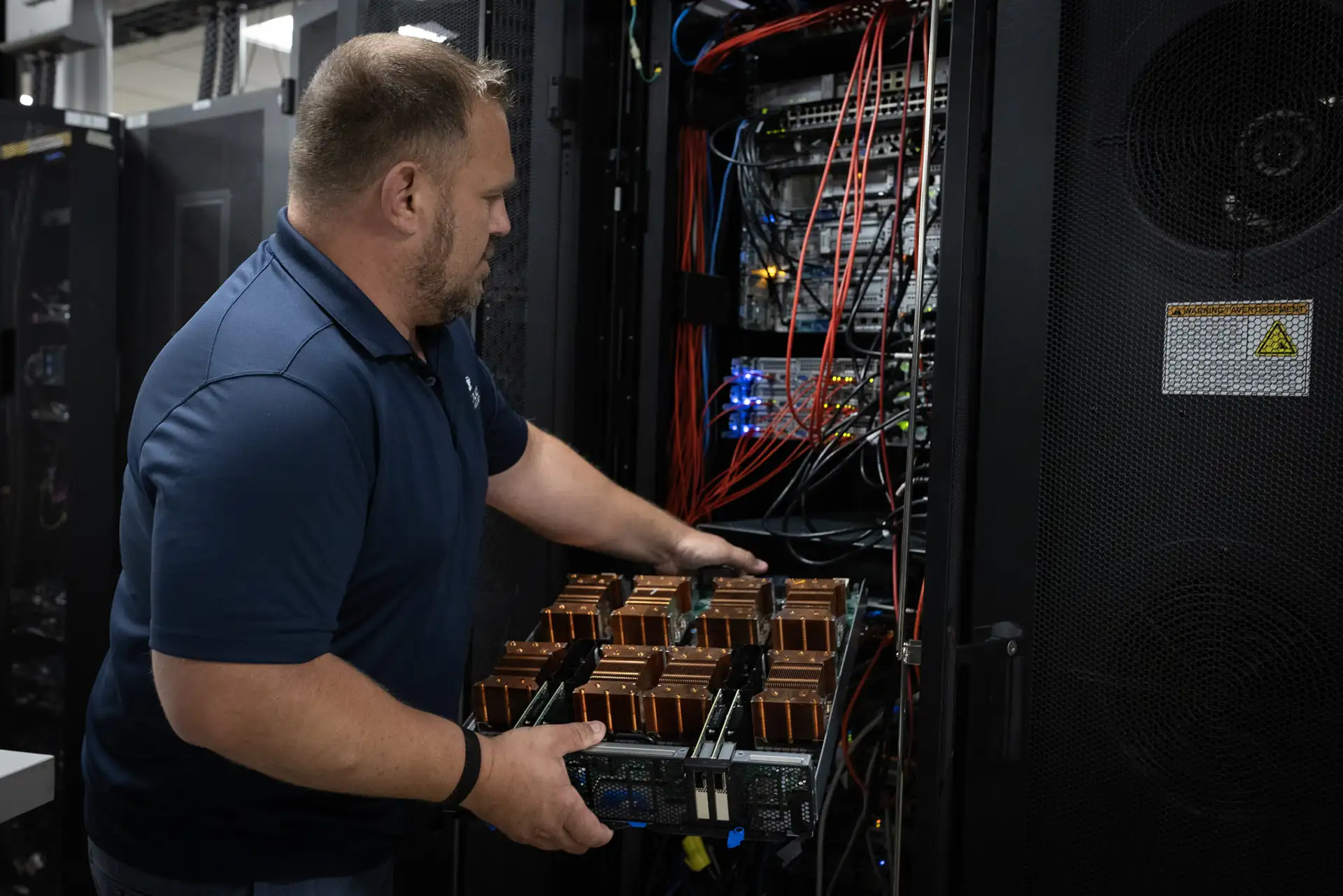 Engineer handling a server tray with copper heat sinks at an open rack in an enterprise x86 private cloud