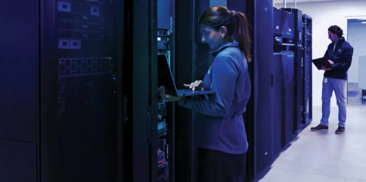 Ingenieurs met een laptop en tablet die aan het werk zijn bij serverracks in een IBM Power-datacenter voor private cloud